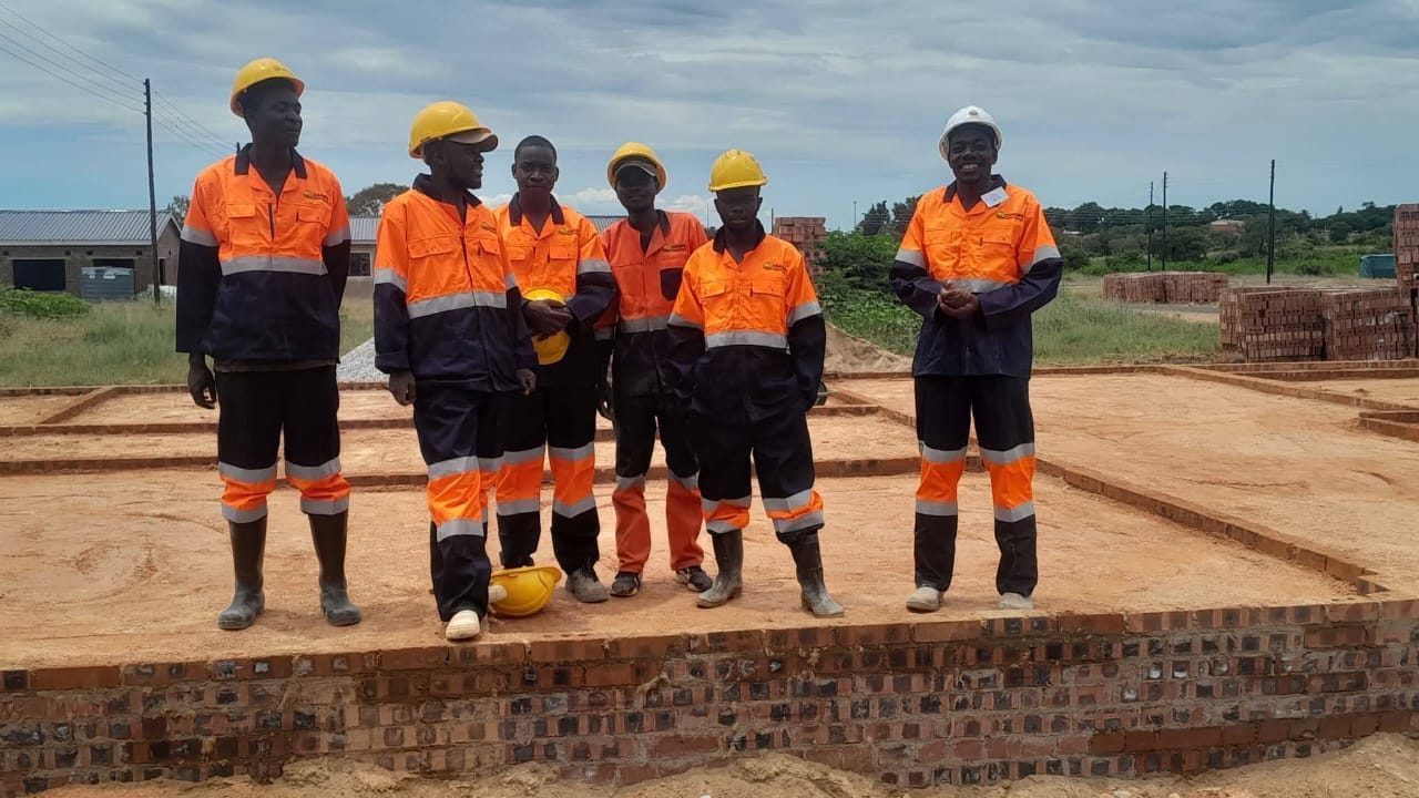 The Champs Construction team in hard hats and orange overalls on a new foundation slab