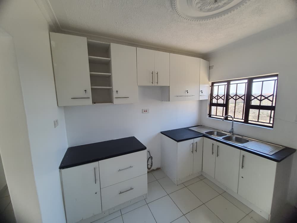 A fitted kitchen with white cupboards and a black worktop