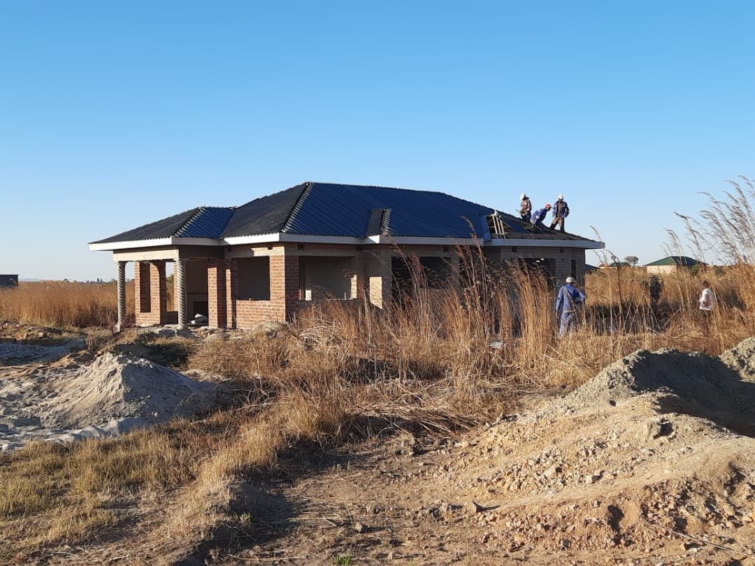 Builders fixing the roof on a Champs house under construction